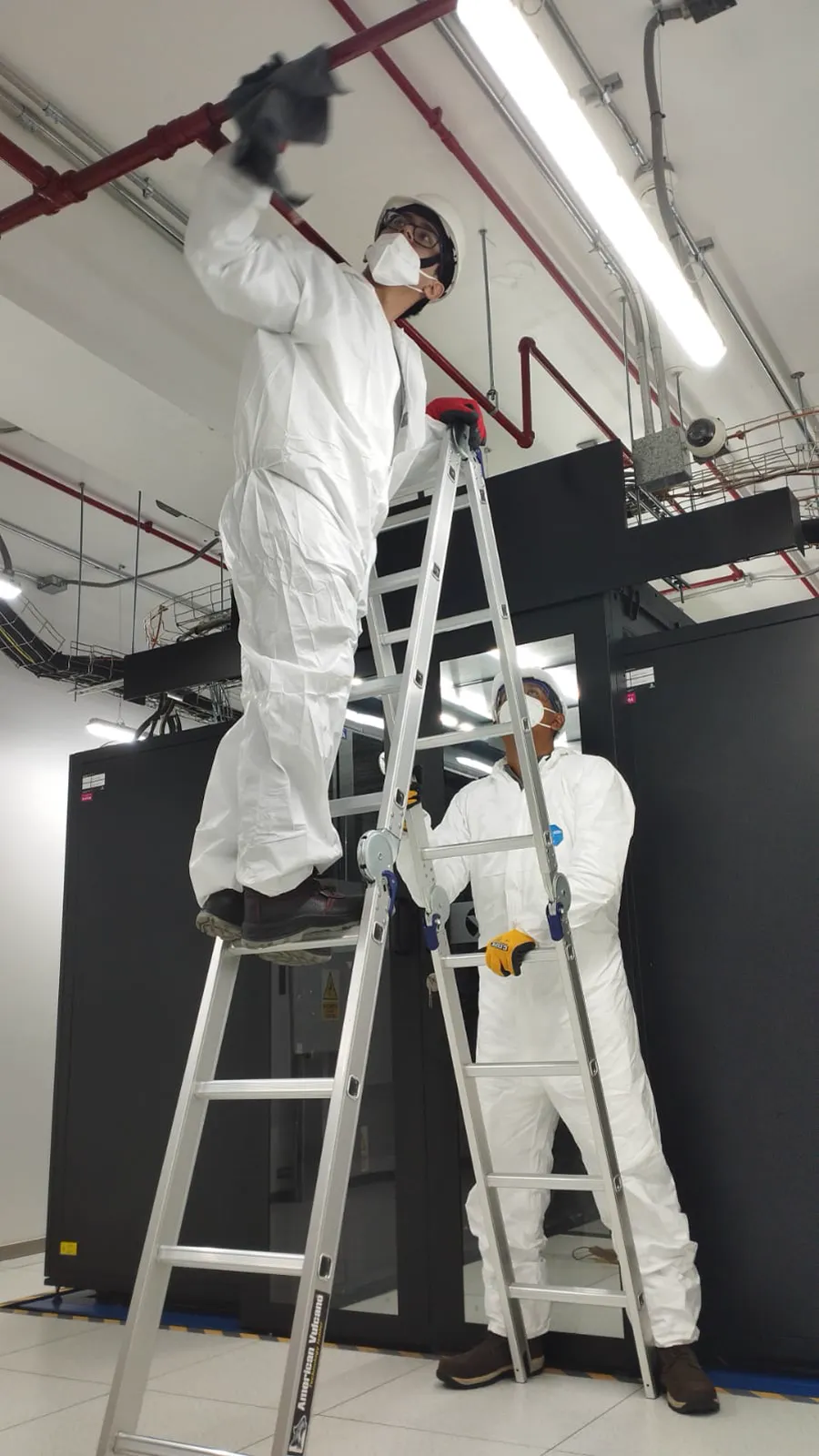 Técnicos realizando limpieza de infraestructura elevada en una sala técnica